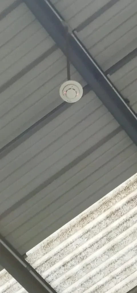Detector puntual de humo instalado en techo de nave industrial